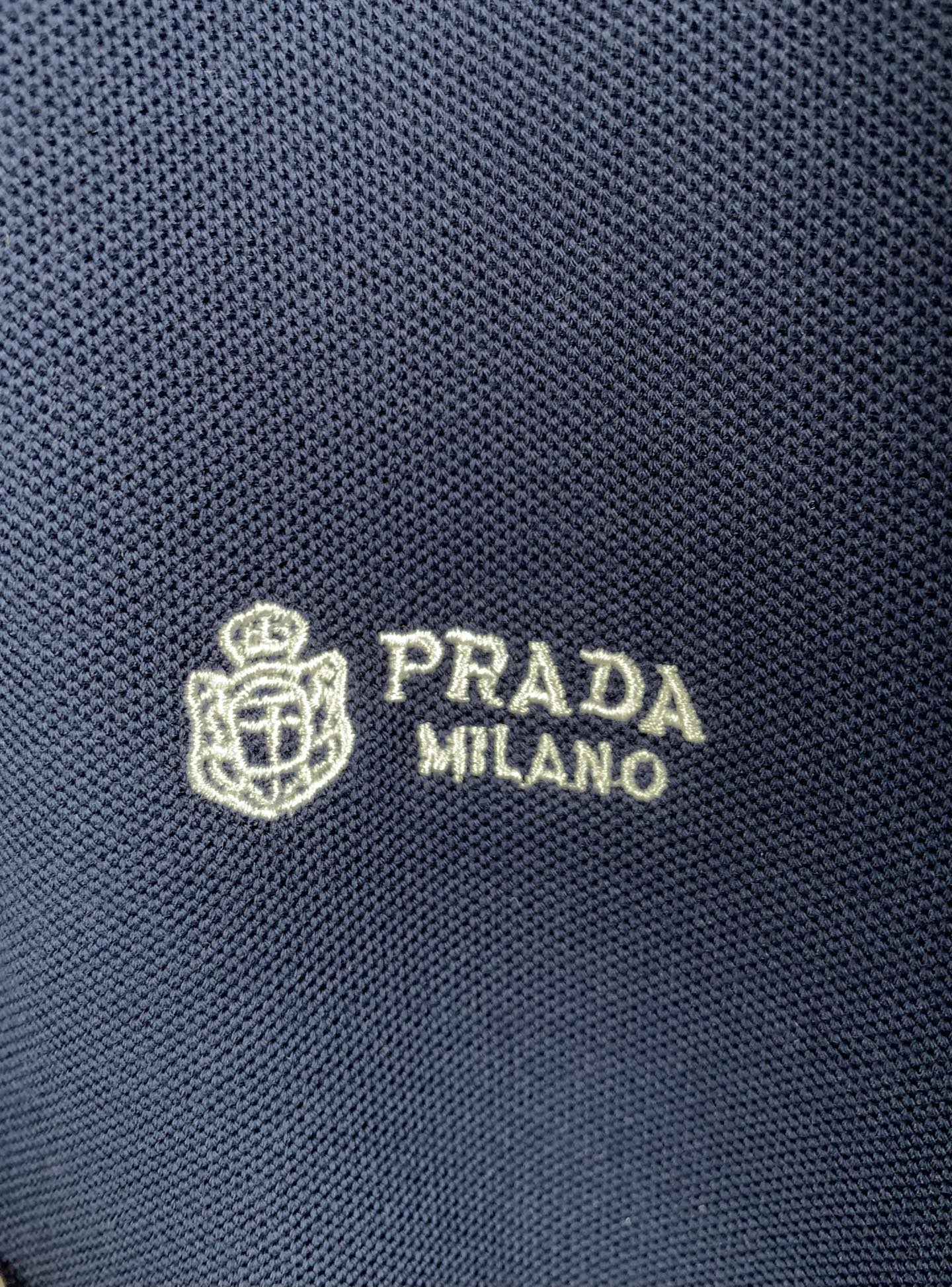 Close-up of Prada Milano logo on navy knit polo fabric