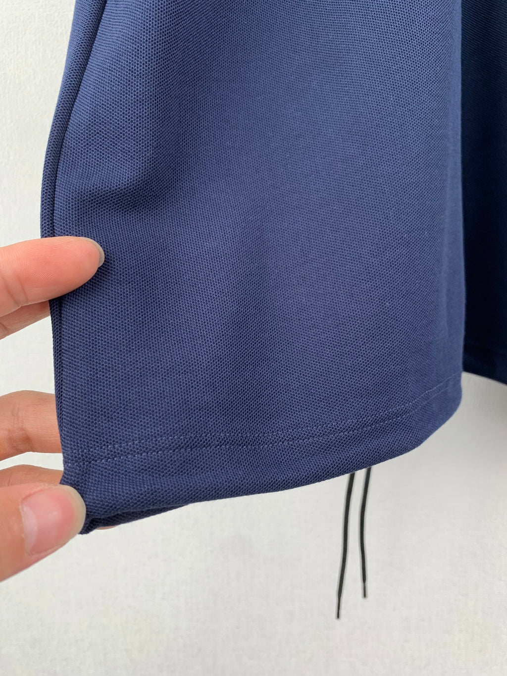 Navy polo shirt hem with small drawstring and knit texture