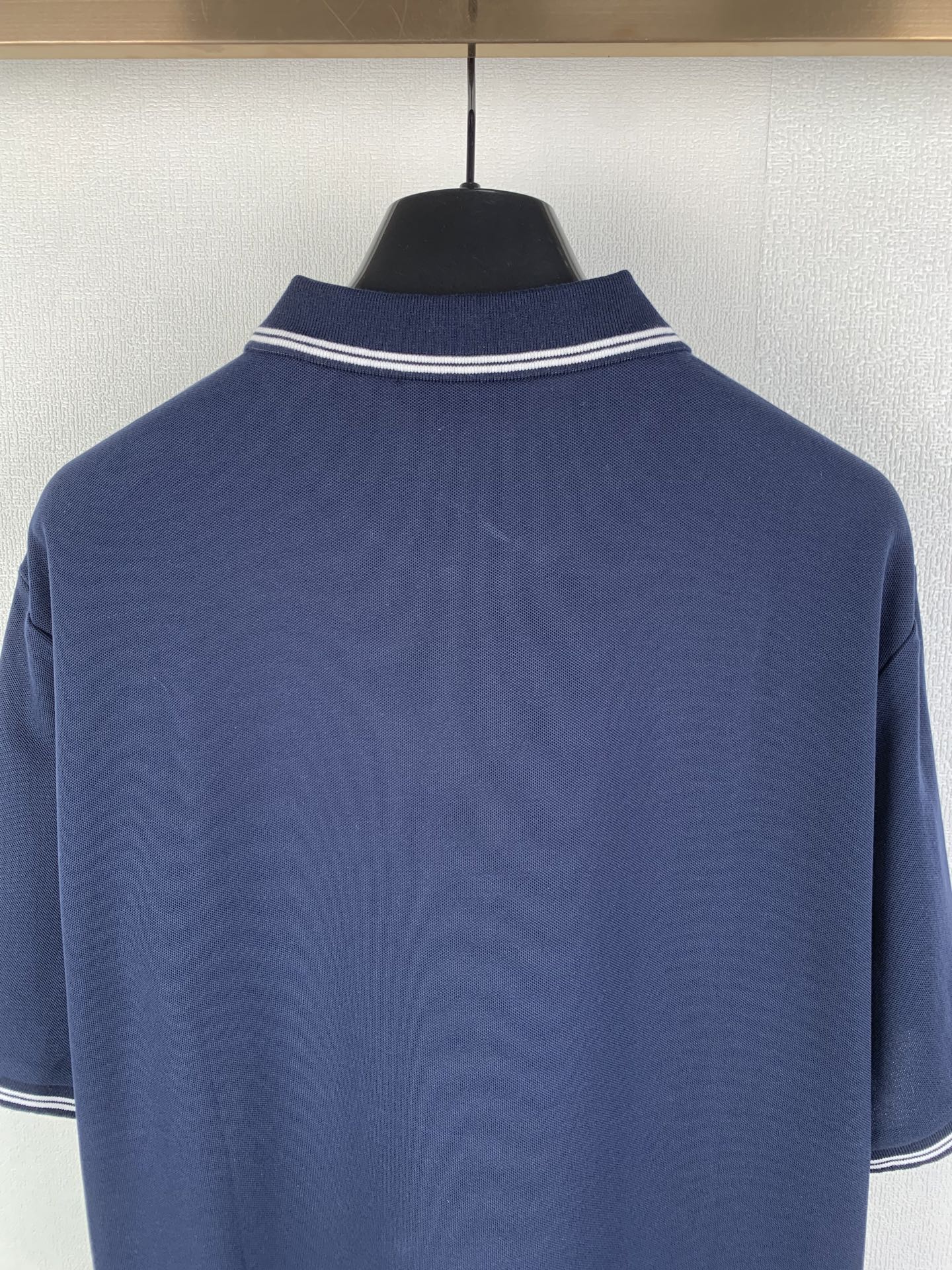 Navy polo shirt neckline with white double-stripe collar trim