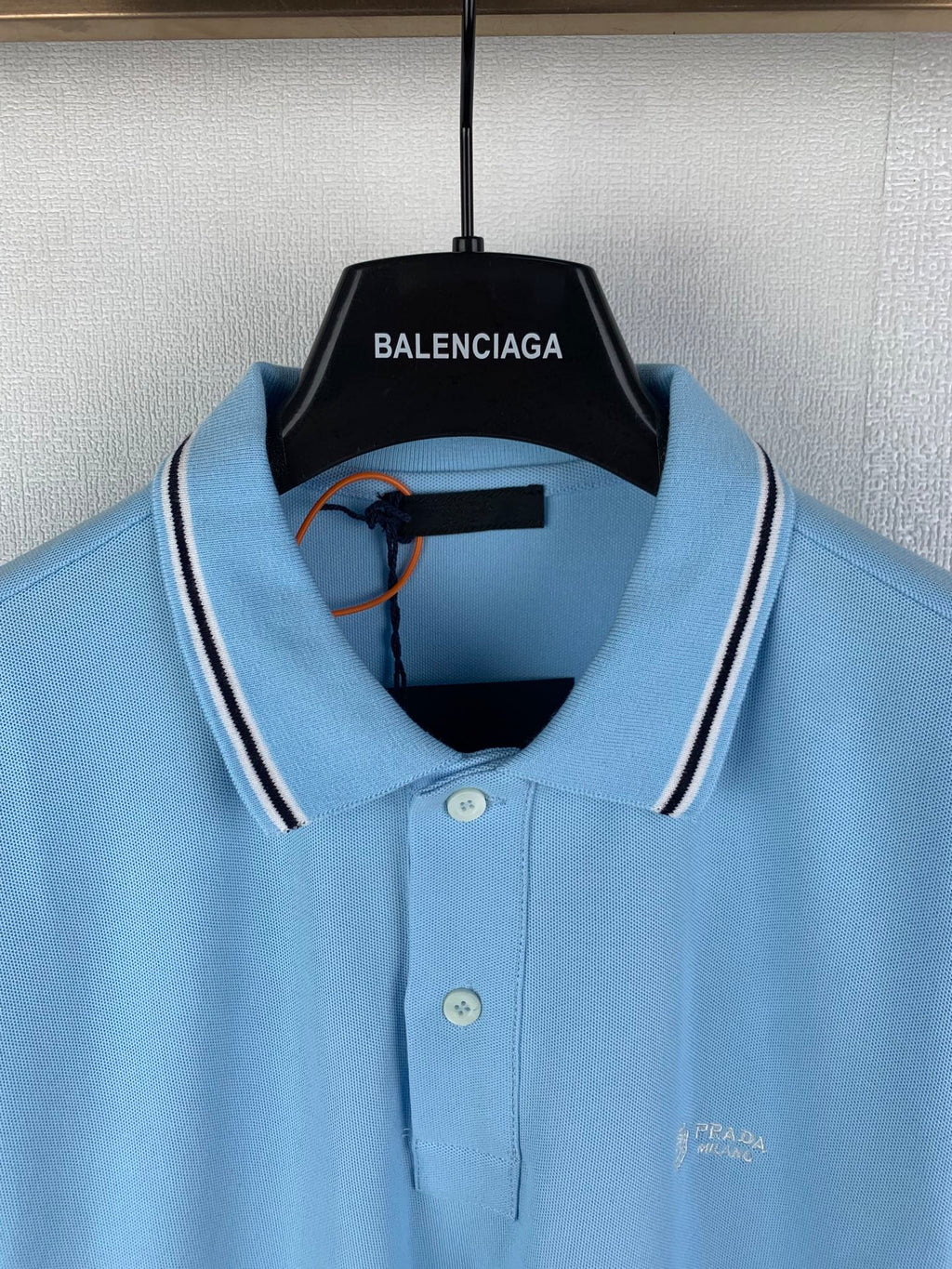 Light blue polo shirt neckline with white-striped collar, buttons, and chest logo