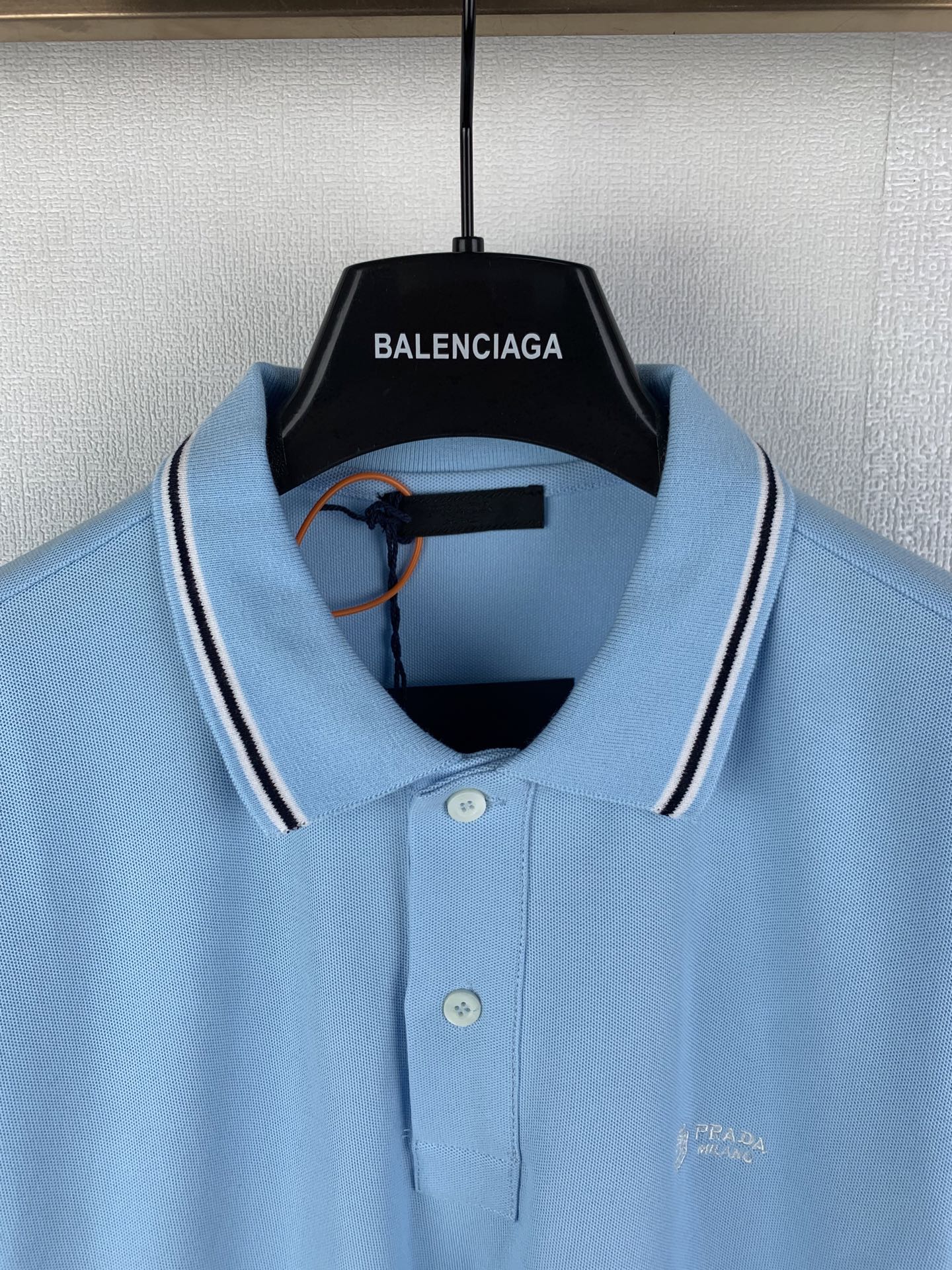 Light blue polo shirt neckline with white-striped collar, buttons, and chest logo