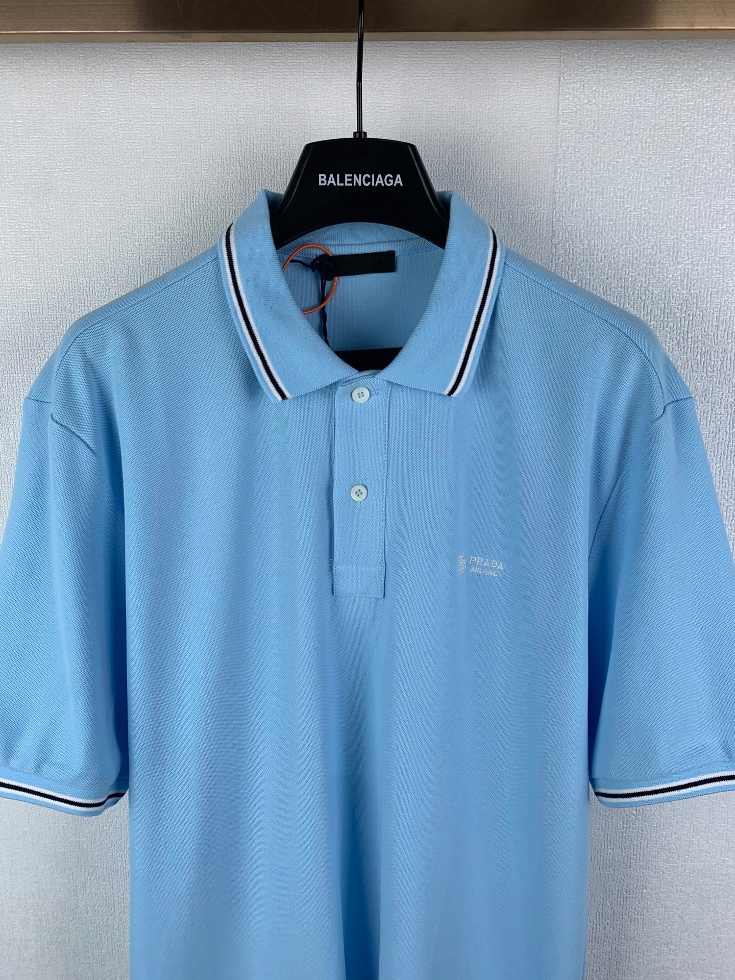 Light blue polo shirt with white-trim collar, button placket, and chest logo