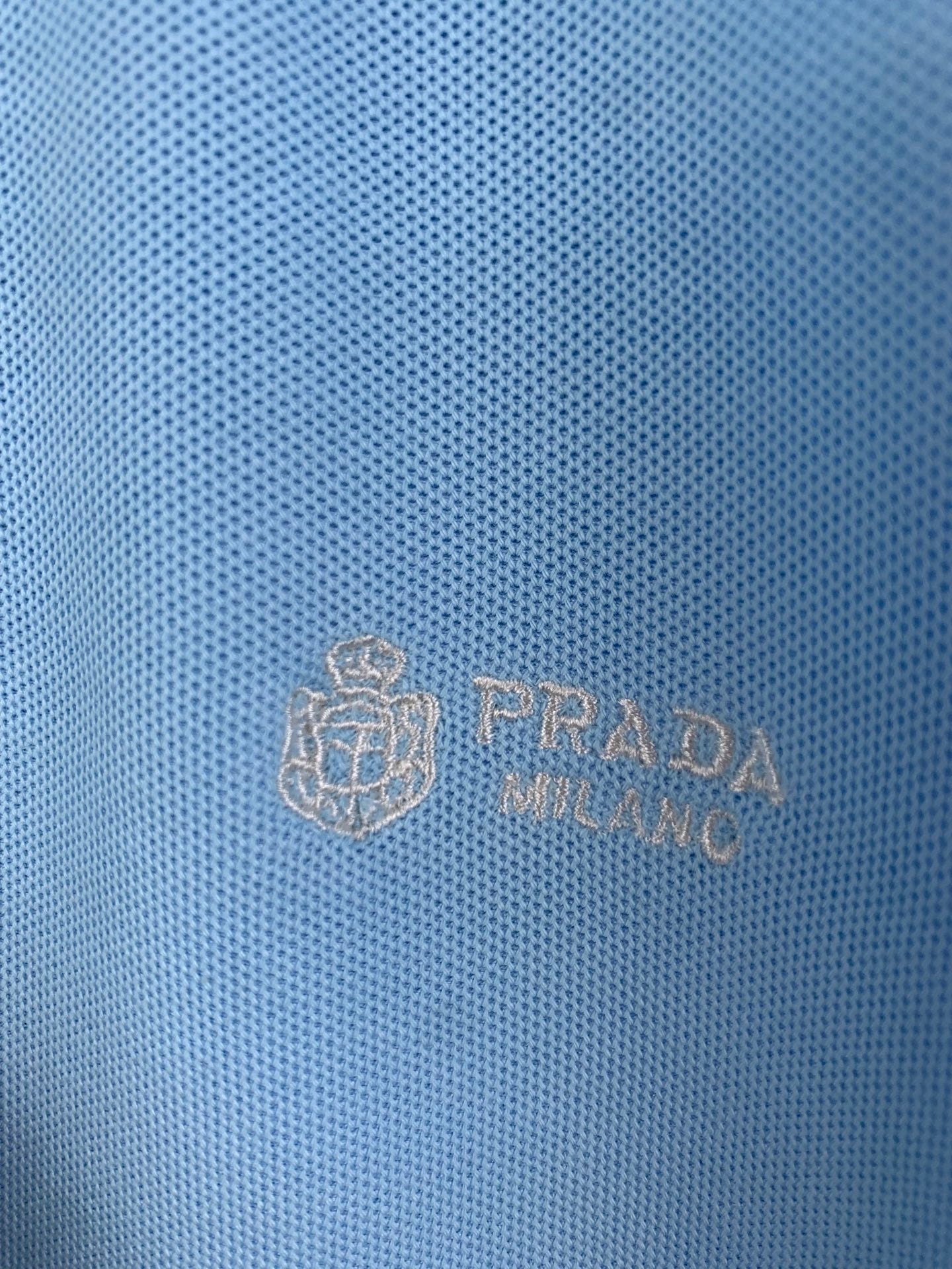 Light blue polo fabric with embossed Prada logo crest