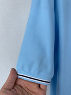 Light blue polo sleeve cuff with white-and-navy striped trim