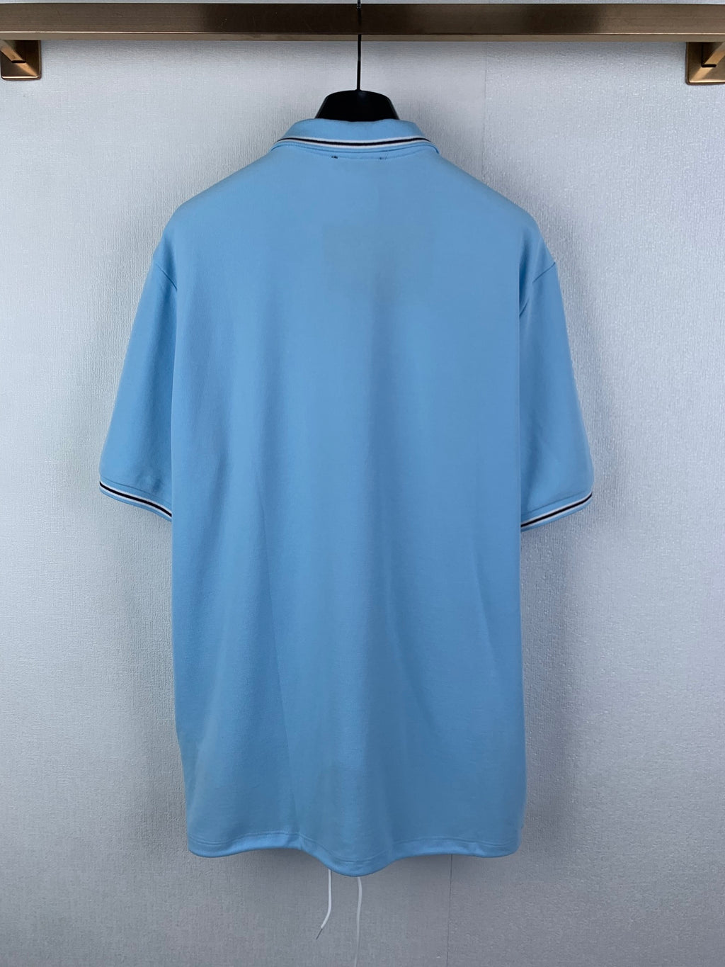 Light blue polo shirt back view with white-trim neckline and short sleeves