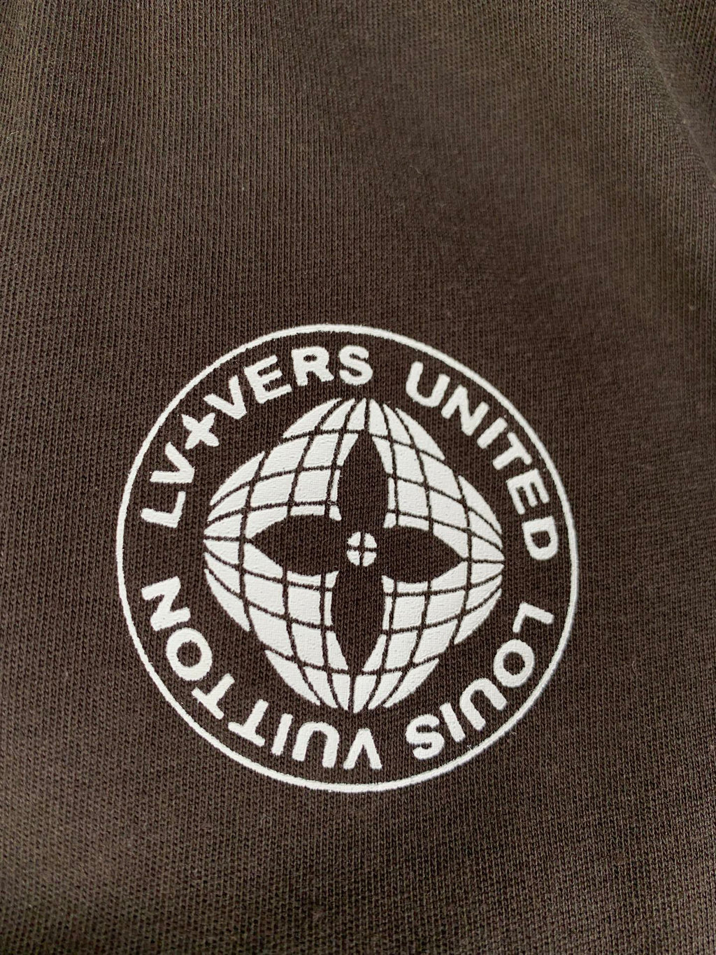 Crest patch on dark brown T-shirt with globe and text "LIVEERS UNITED"
