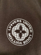 Crest patch on dark brown T-shirt with globe and text "LIVEERS UNITED"