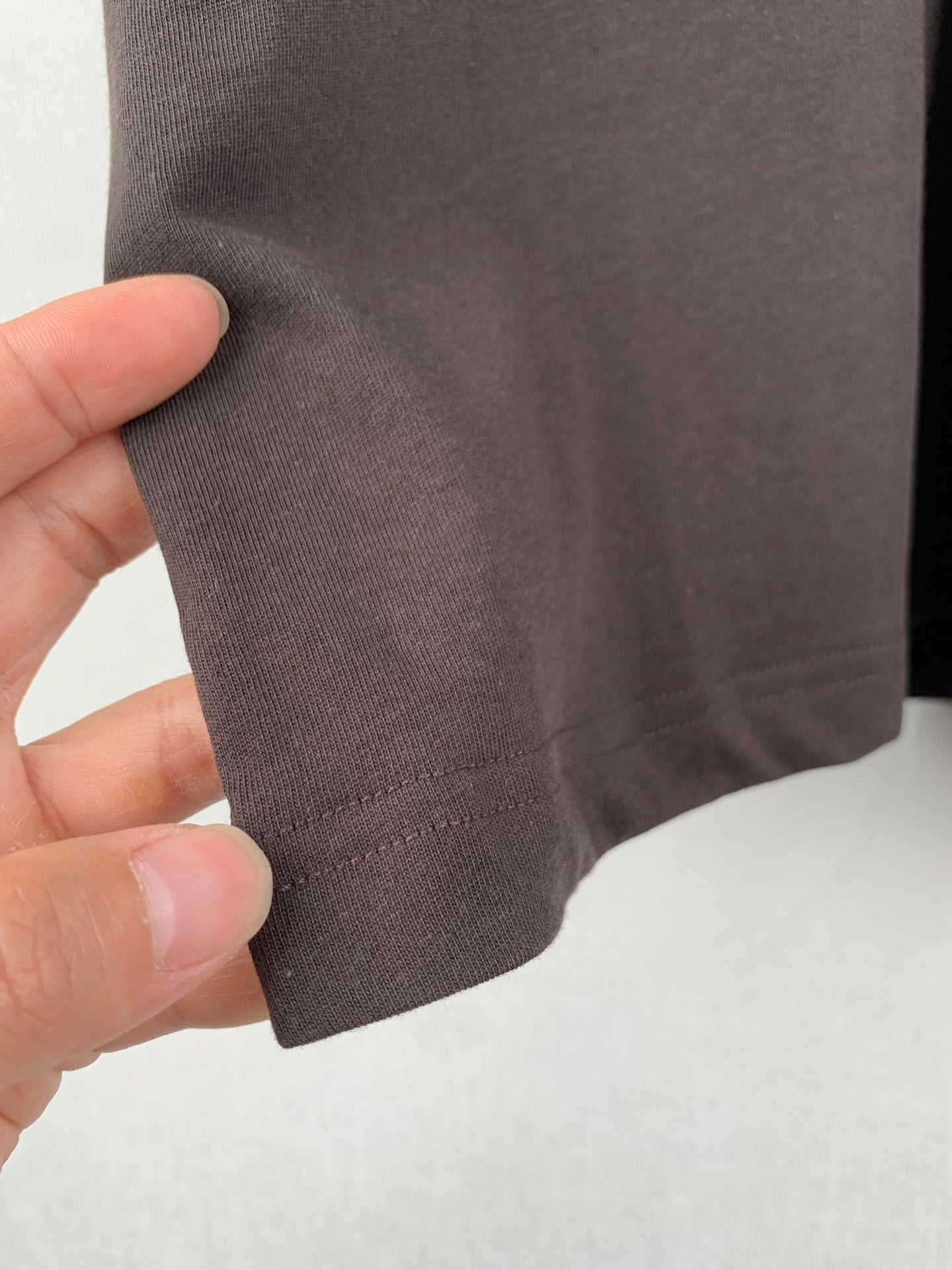 Close-up of dark brown T-shirt hem stitching with fabric texture detail