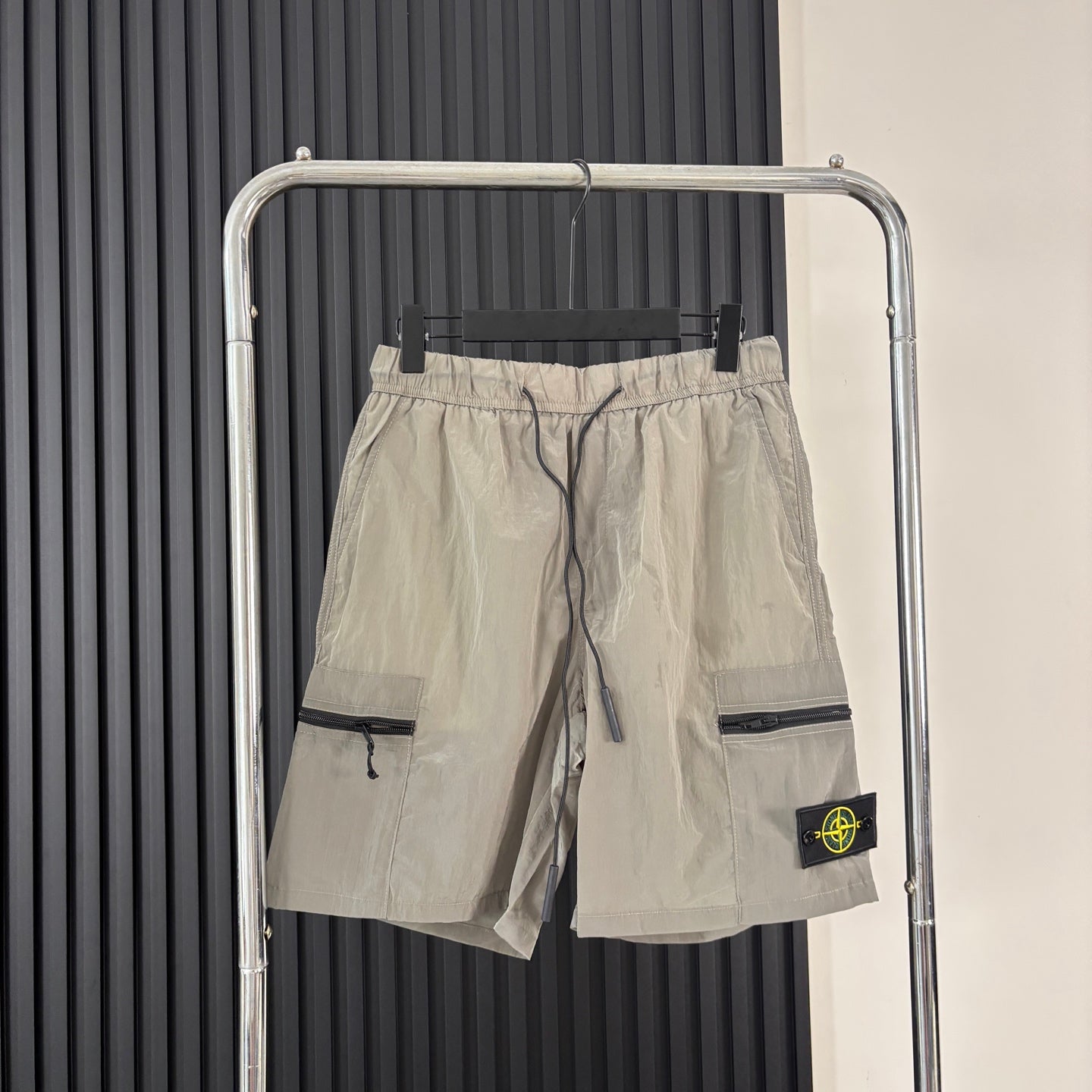 Beige cargo shorts with drawstring waist, side pockets, and Stone Island patch