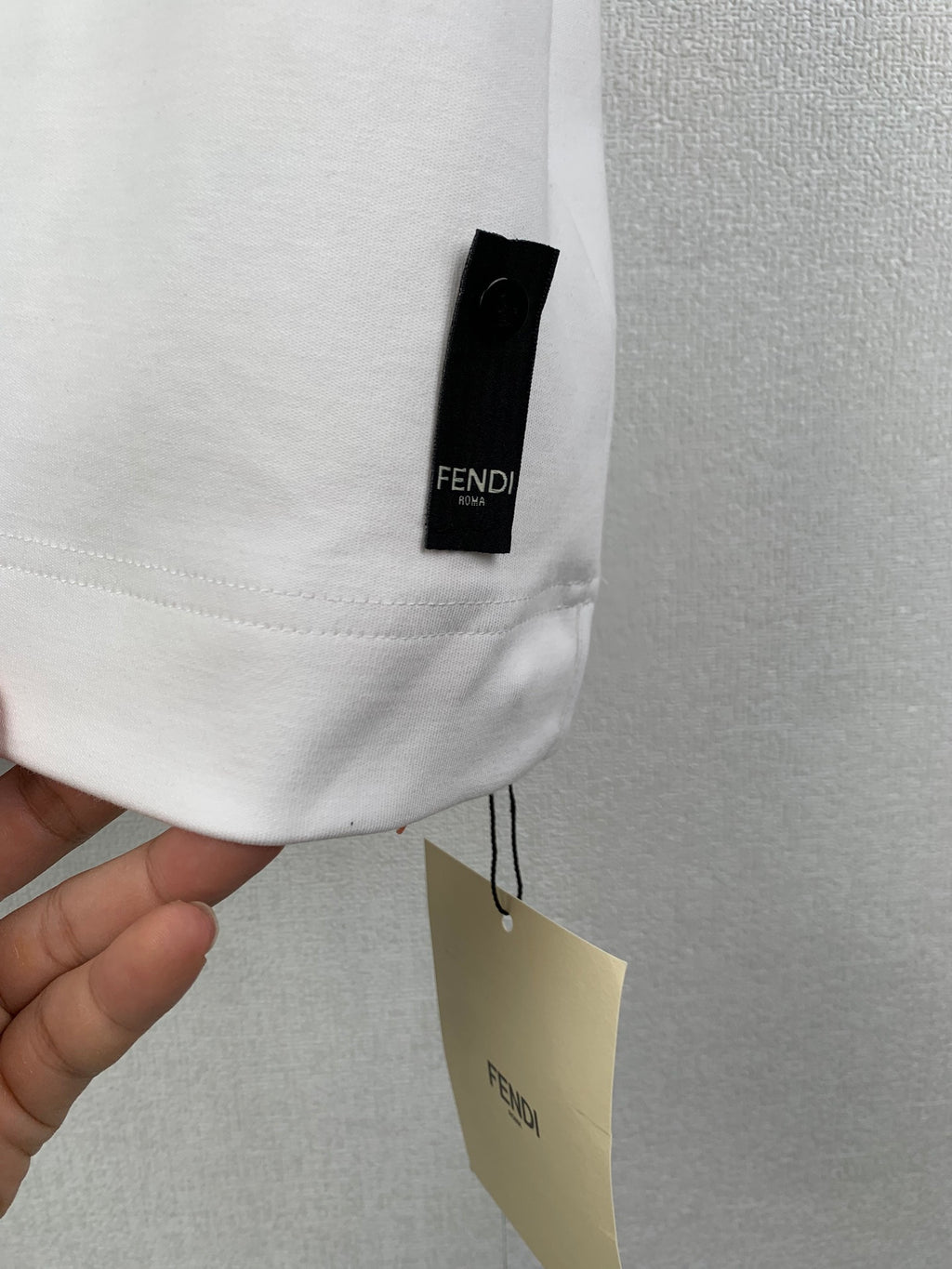 White Fendi T-shirt sleeve tag with FENDI label attached