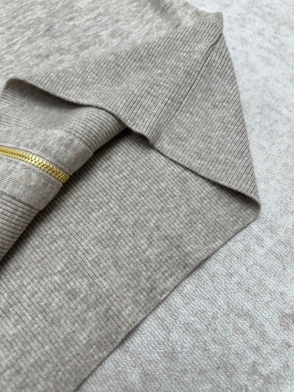 Ribbed cuff and sleeve end on heather gray sweater with gold zipper trim