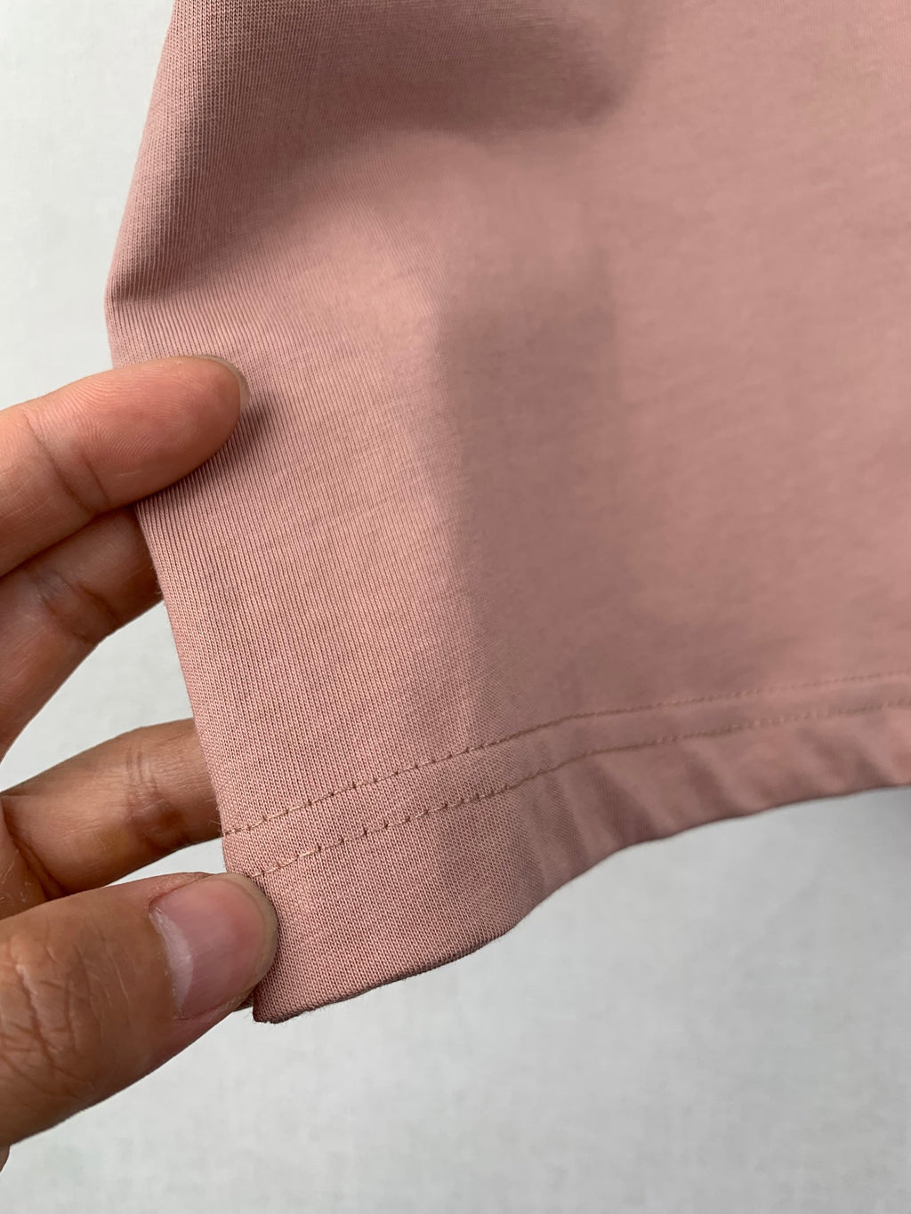 Dusty pink T-shirt hem with double-stitched edge and seam