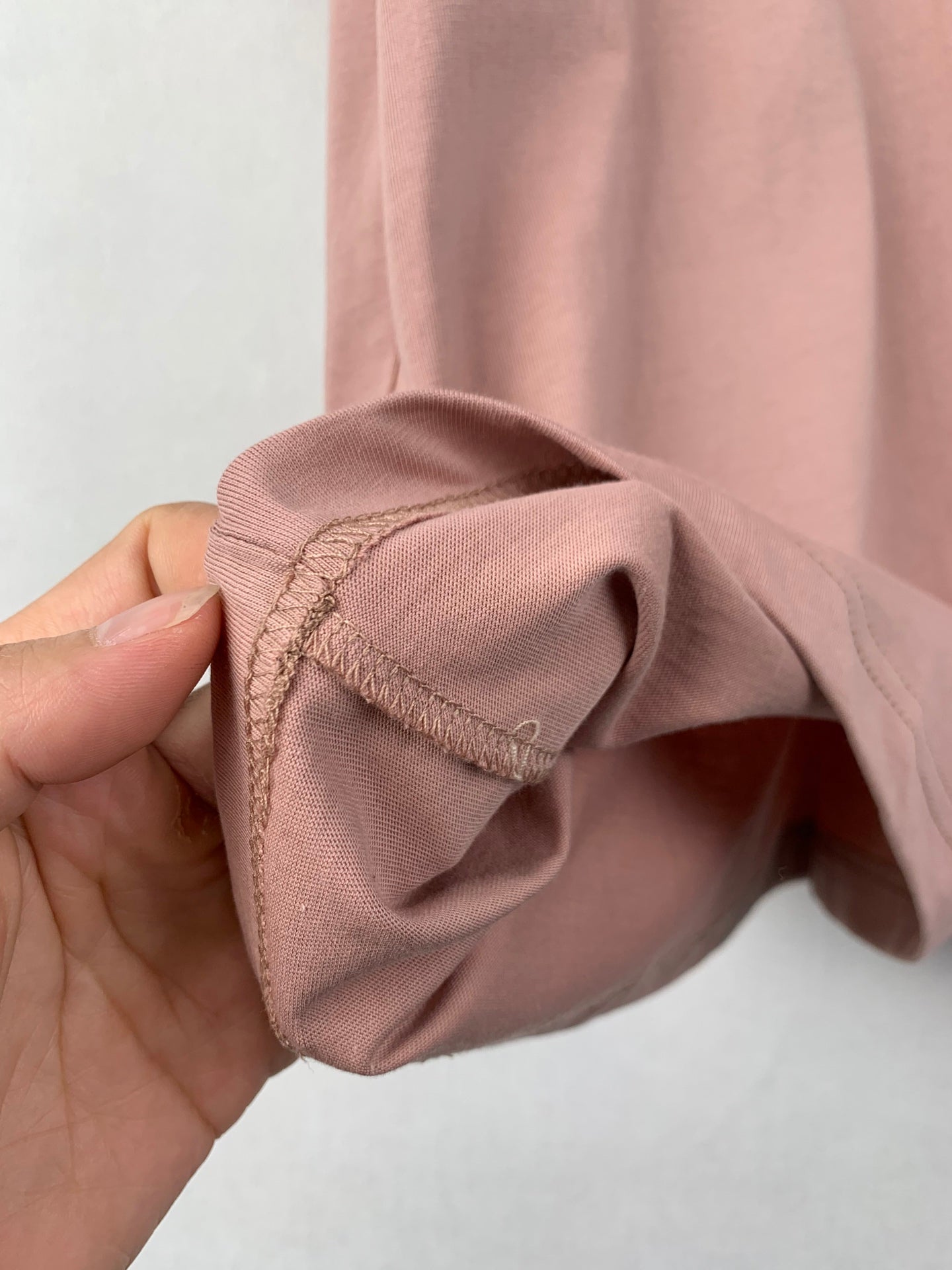 Dusty pink T-shirt sleeve cuff close-up with gathered stitching