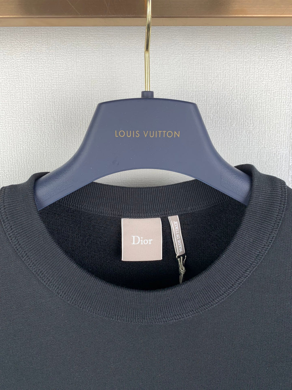 Black crewneck sweatshirt with Dior neck label and Louis Vuitton hanger