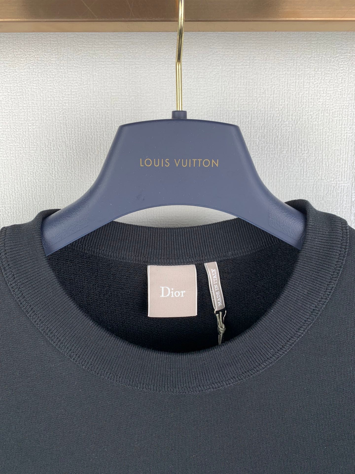 Black crewneck sweatshirt with Dior neck label and Louis Vuitton hanger