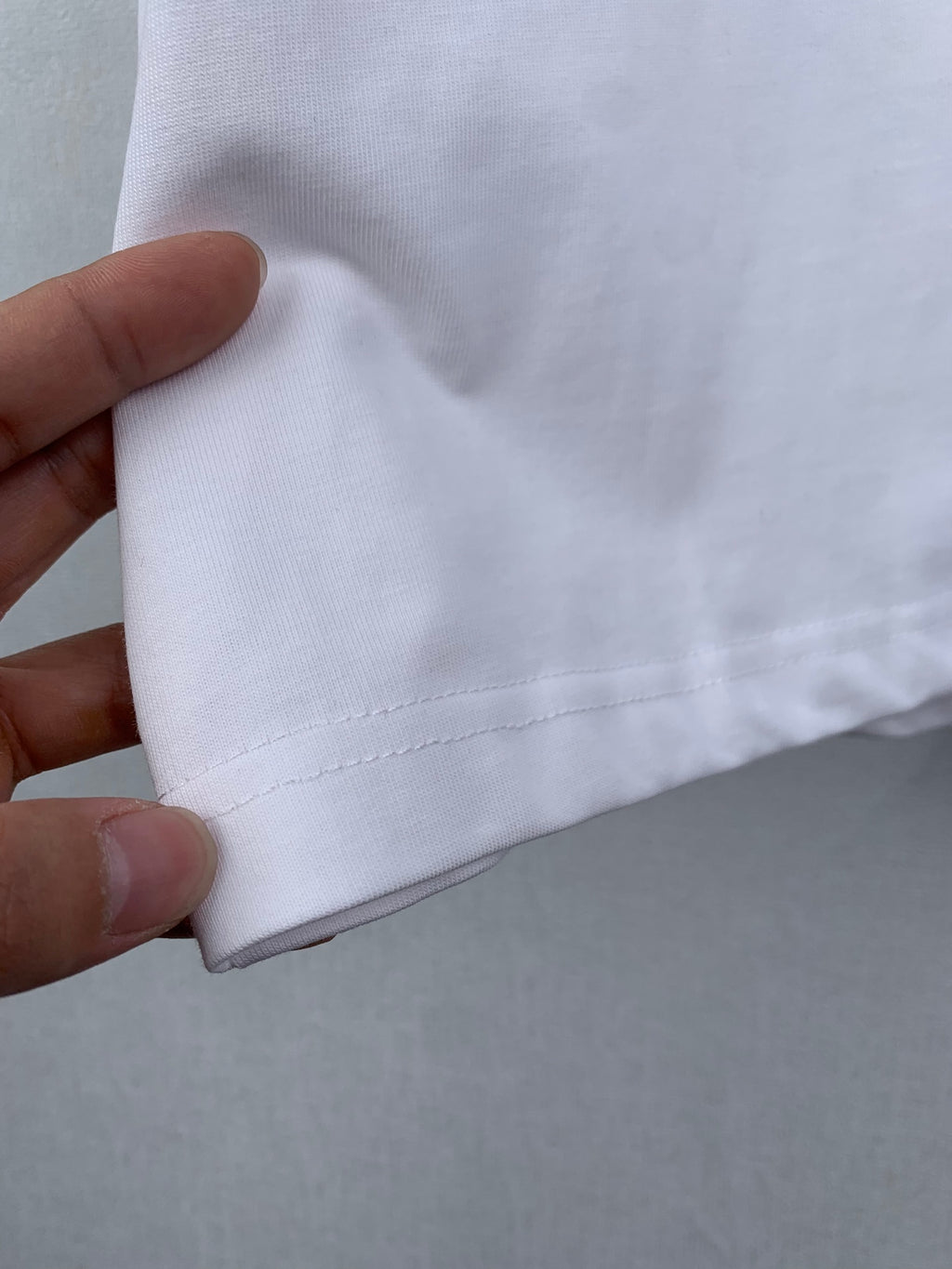 Off white T-shirt side seam close-up with stitched hem