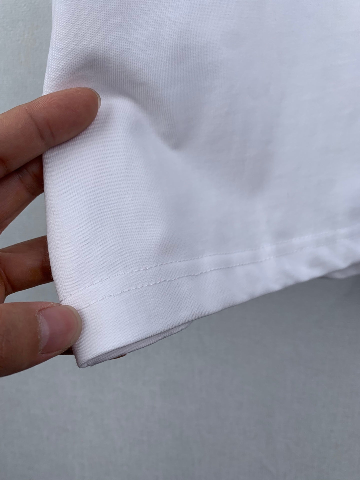 Off white T-shirt side seam close-up with stitched hem