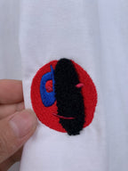 Off white T-shirt with embroidered red circular logo and black-blue figure