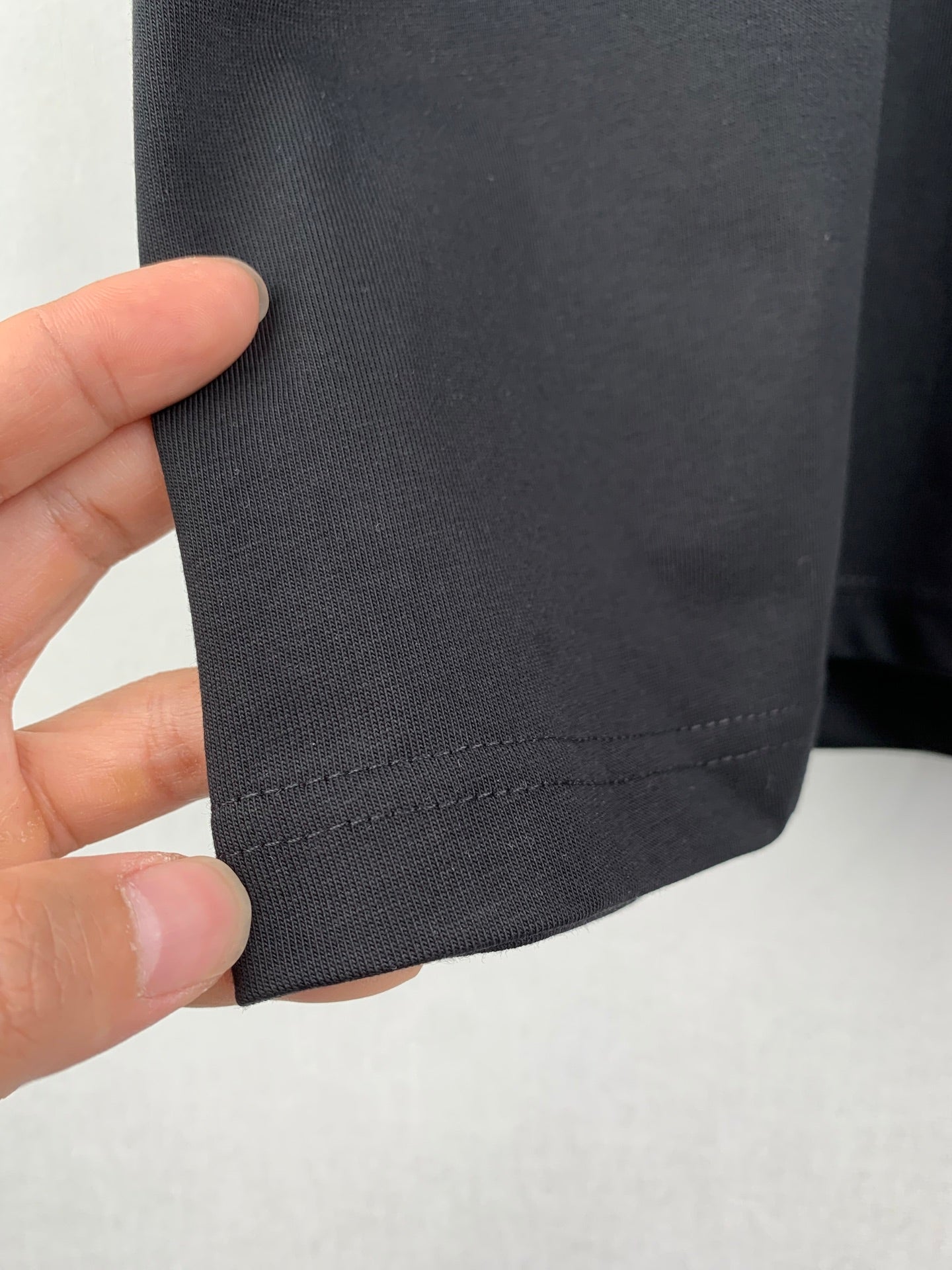 Close-up of dark charcoal T-shirt hem stitching and fabric texture