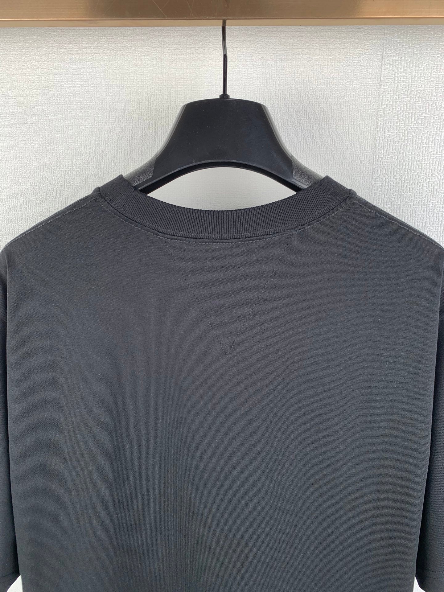 Crewneck T-shirt collar detail in dark charcoal with reinforced stitching at neckline