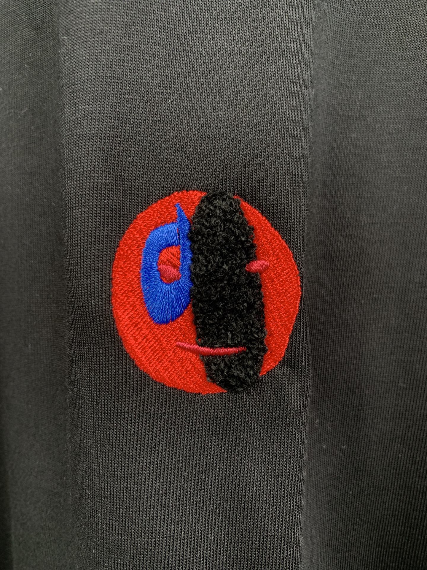 Close-up chest logo on dark charcoal crewneck T-shirt with red and blue graphic