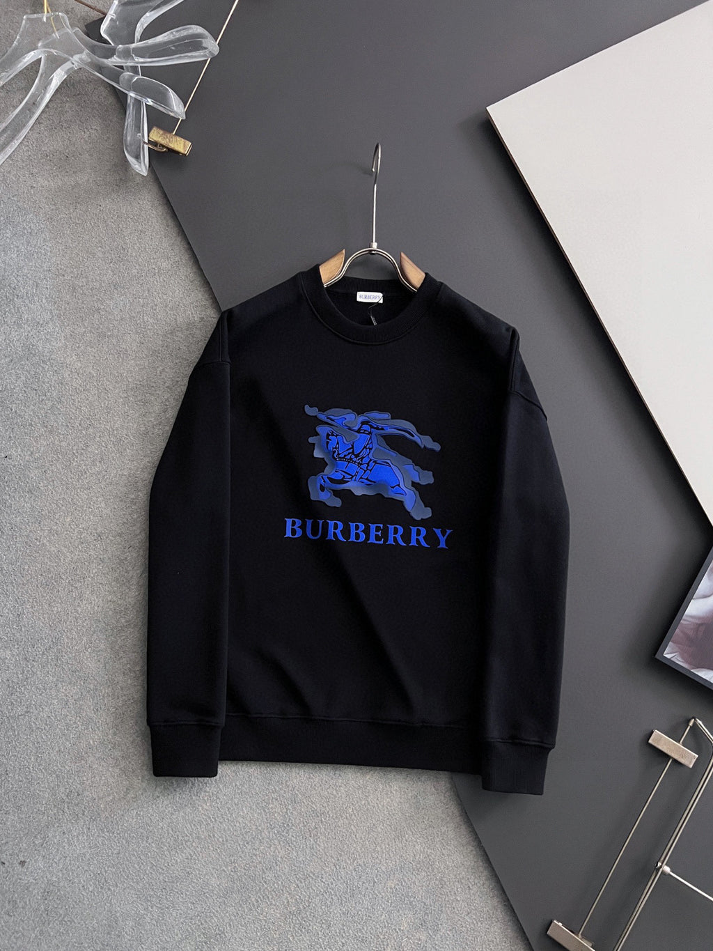 Black sweatshirt with blue horse graphic and BURBERRY logo on the chest.