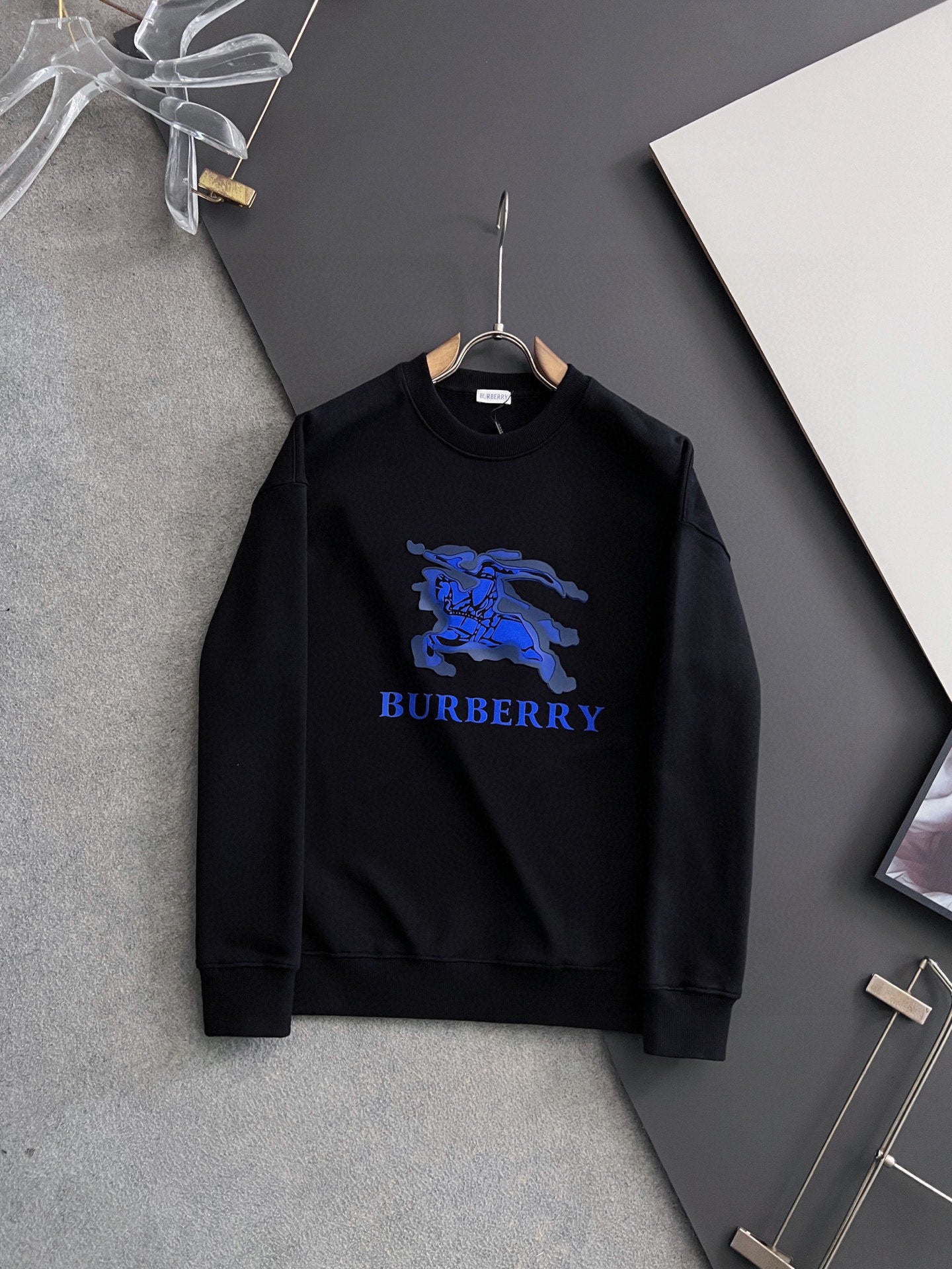 Black sweatshirt with blue horse graphic and BURBERRY logo on the chest.