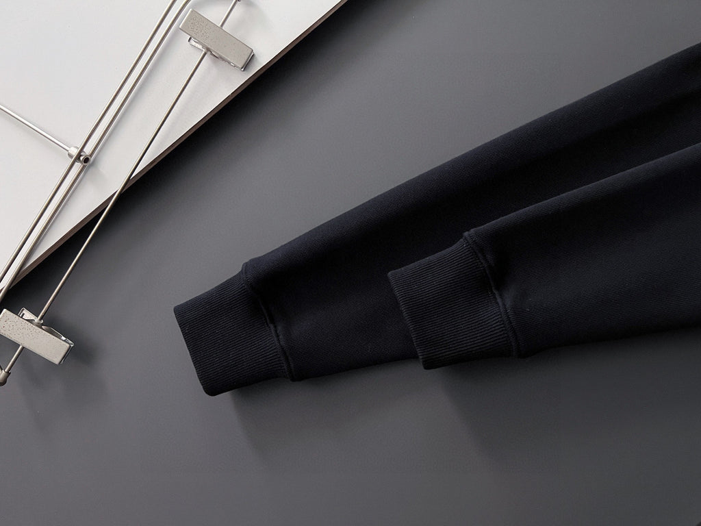Black sweatshirt sleeve cuff and hem detail, shown folded on a hanger.