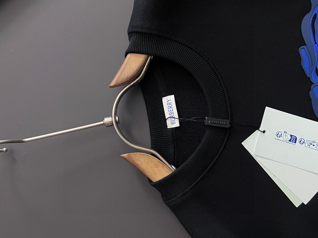 Black sweatshirt hooded neck opening with small white interior tag.