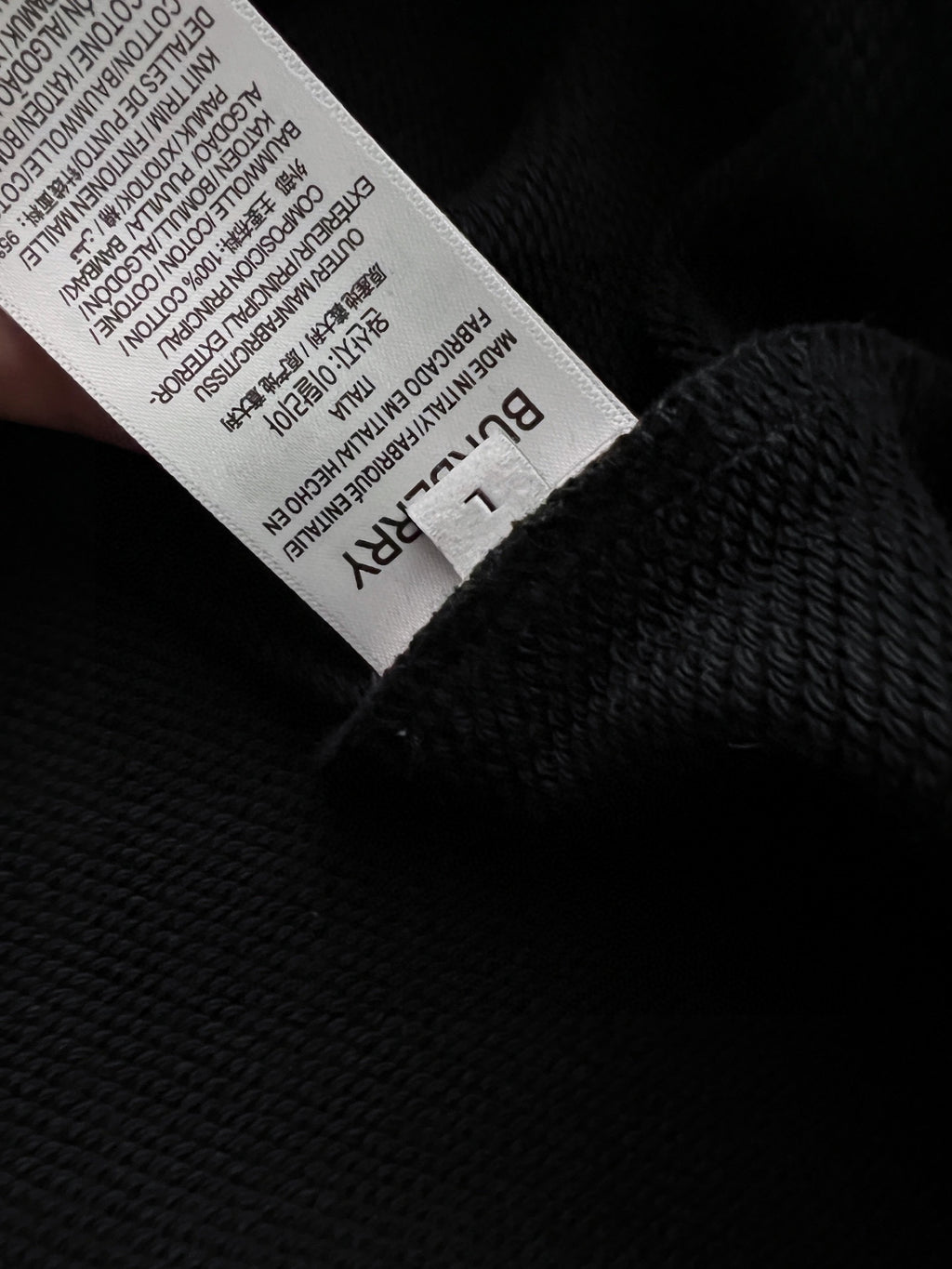 Black sweatshirt with white size label inside the neck opening.