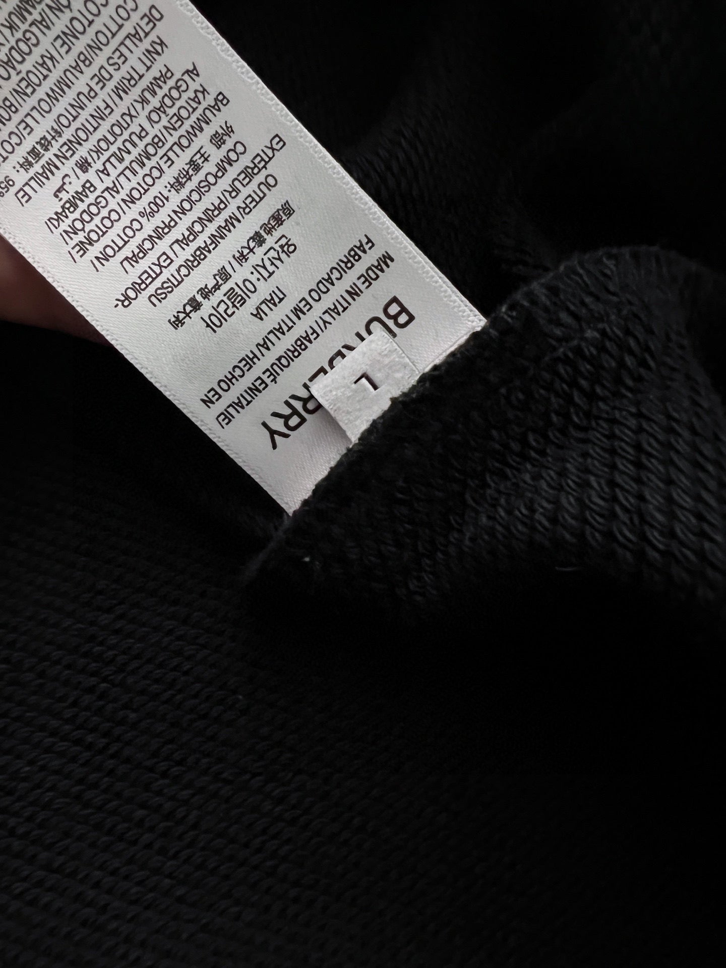Black sweatshirt with white size label inside the neck opening.