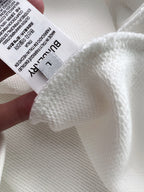 Close-up of white knit fabric texture with care label on sweatshirt
