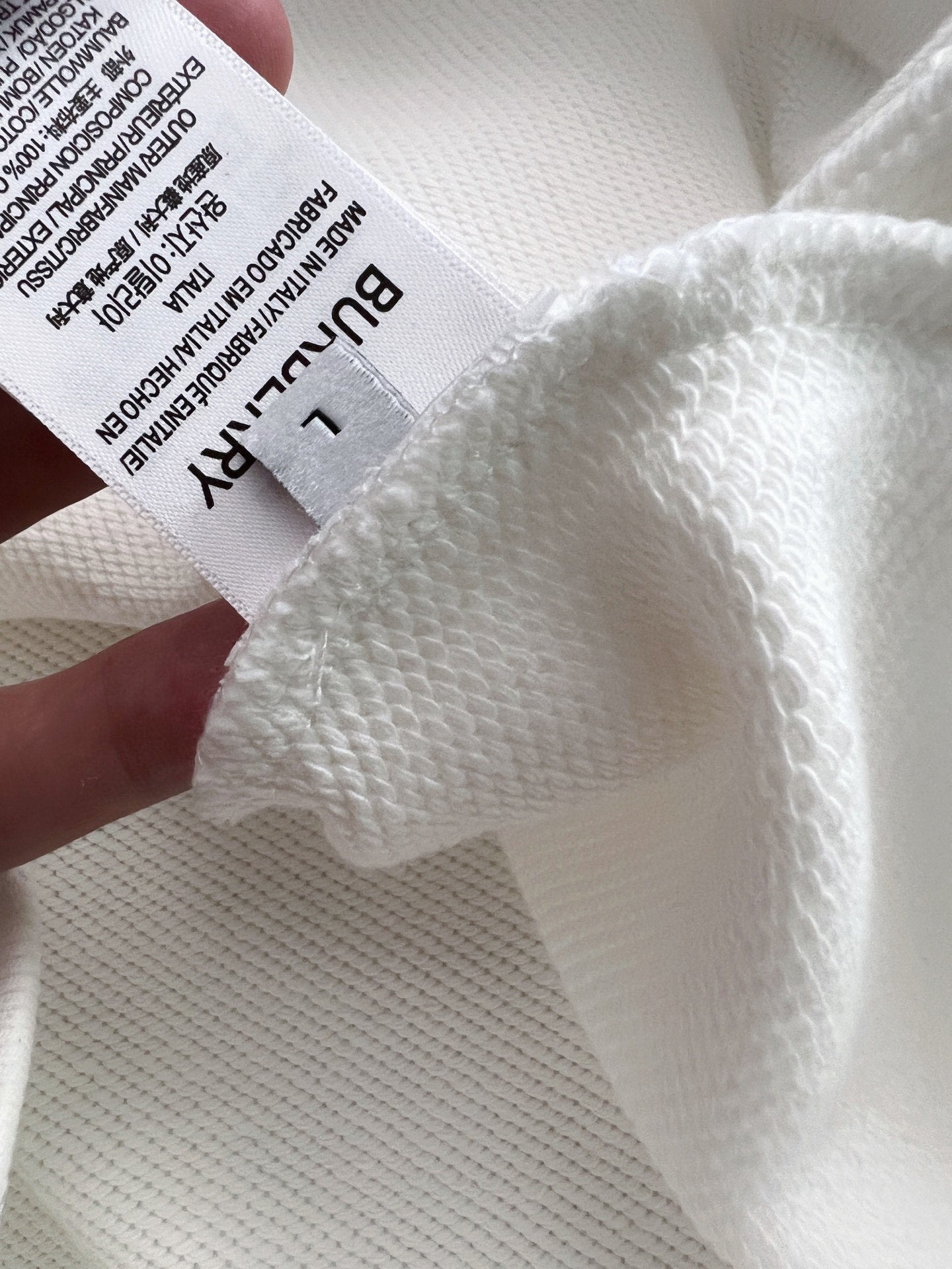 Close-up of white knit fabric texture with care label on sweatshirt