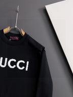 Black Gucci crewneck sweatshirt close-up of white “GUCCI” logo on chest