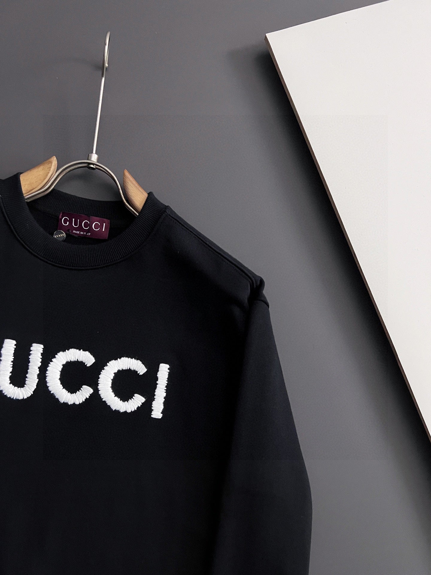 Black Gucci crewneck sweatshirt close-up of white “GUCCI” logo on chest