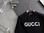 Black Gucci crewneck sweatshirt with white “GUCCI” front logo on hanger