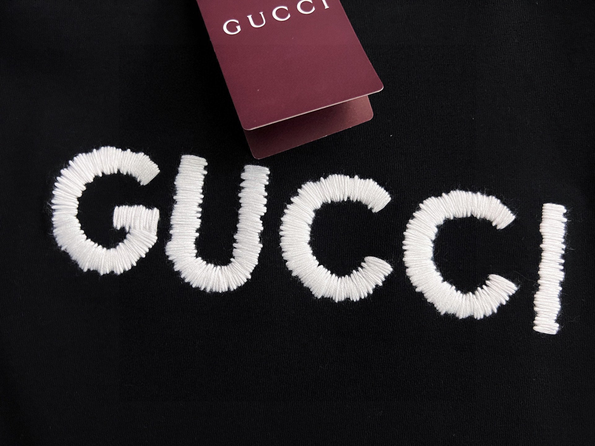 Black Gucci sweatshirt with full white embroidered “GUCCI” logo lettering