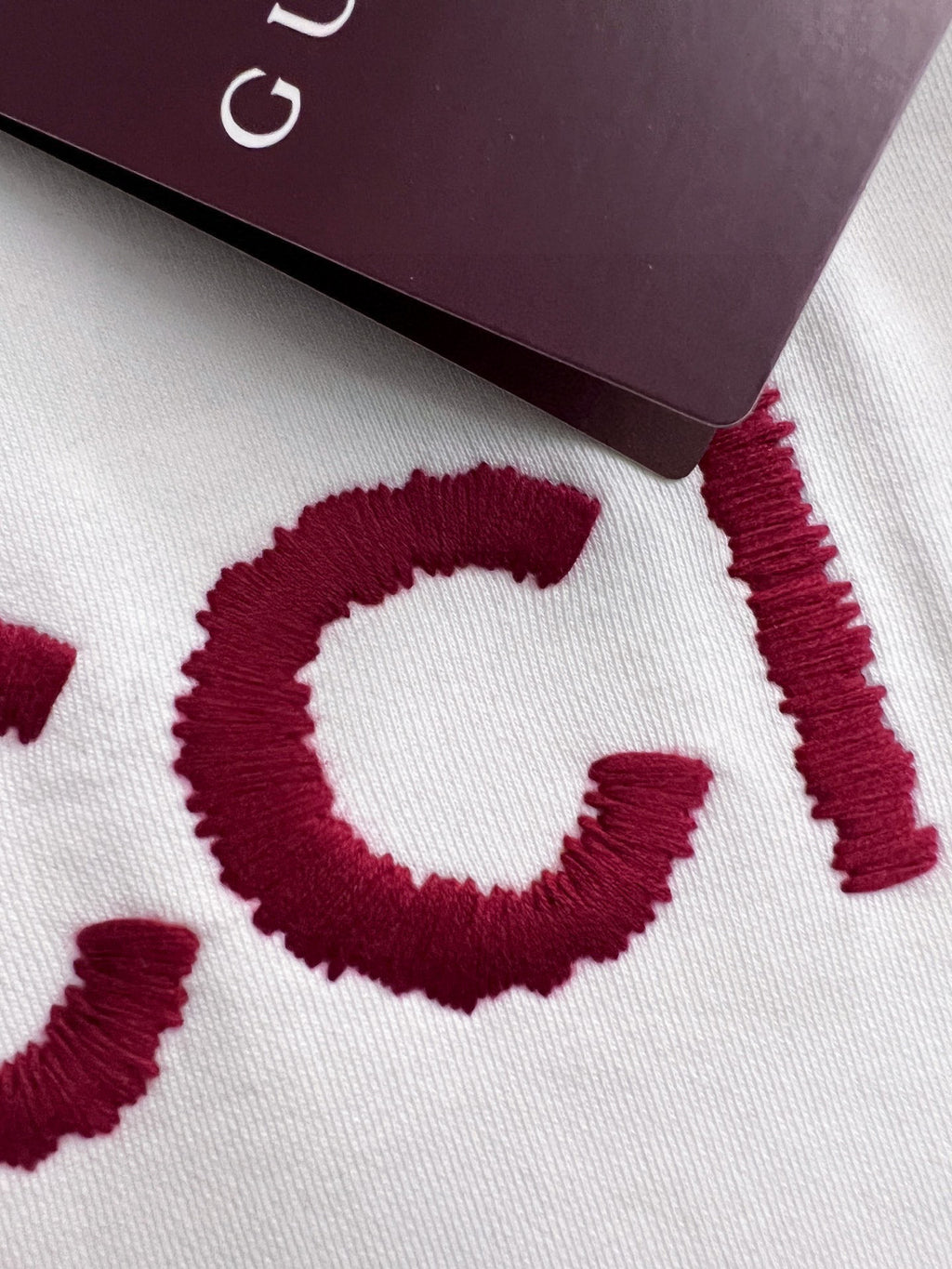 White sweatshirt fabric close-up with red GUCCI lettering