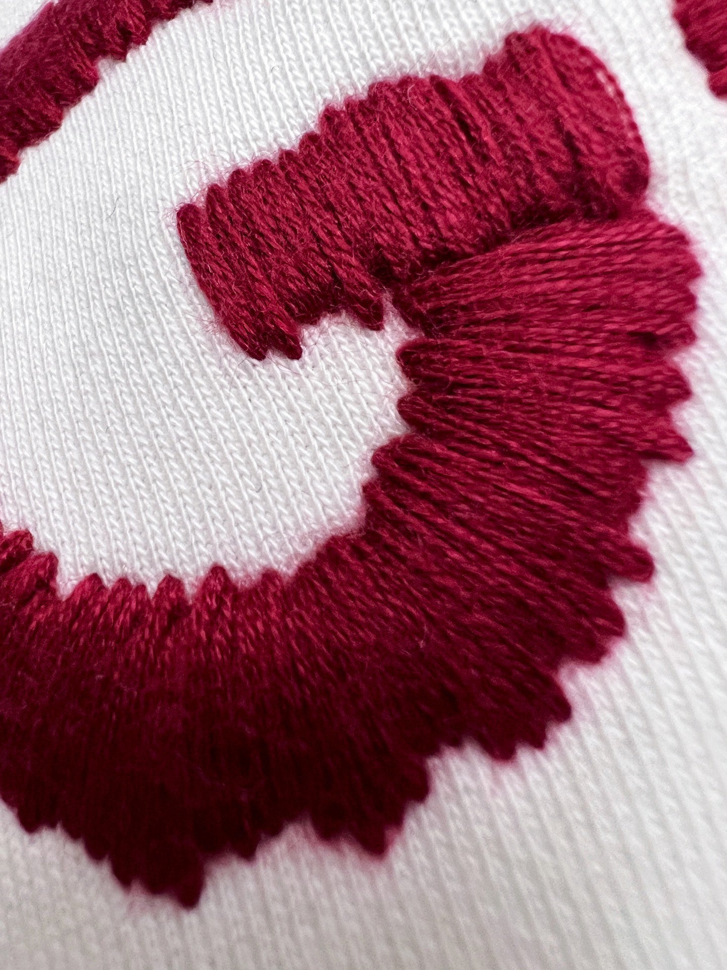 White knit fabric close-up with bold burgundy GUCCI lettering