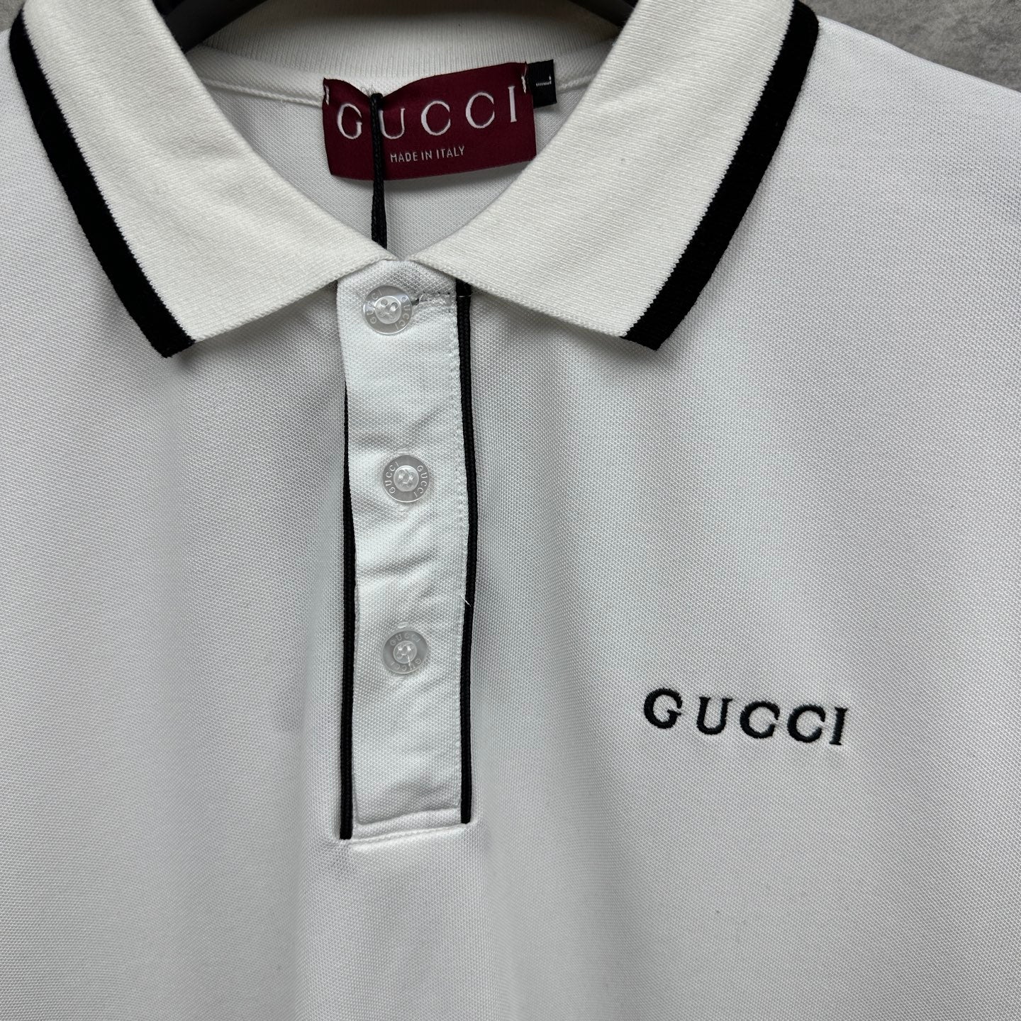 Gucci polo shirt collar detail, white with black trim and button placket.