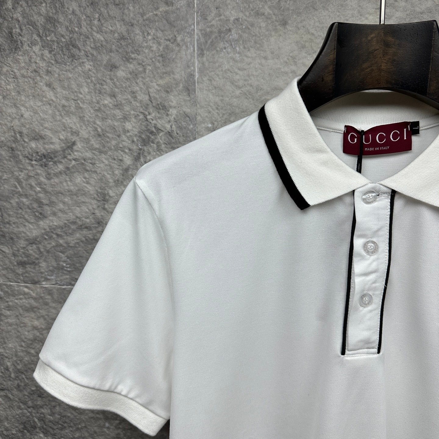 Gucci short-sleeve polo shirt neckline, white with black-trim collar and button placket.