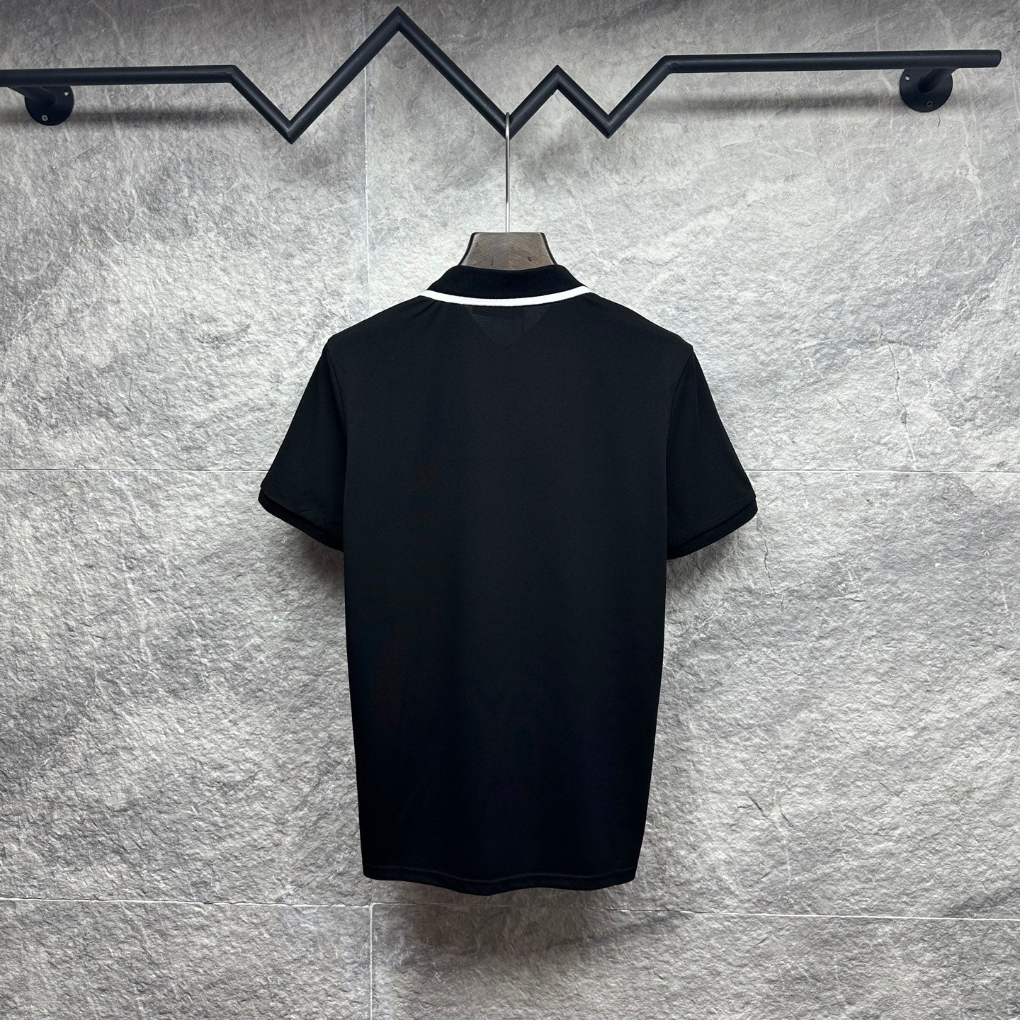 Black polo shirt with white-trim collar and short sleeves, back view
