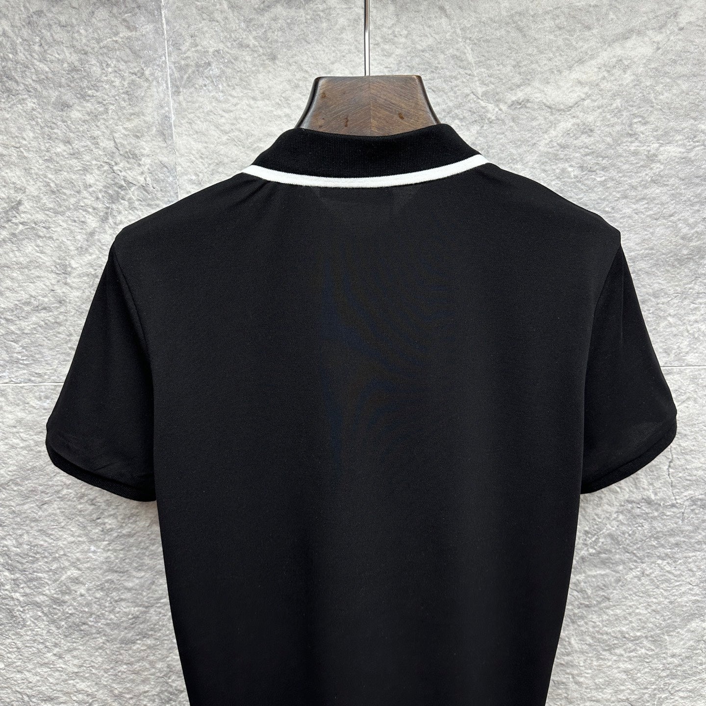 Black polo shirt back view with white collar trim
