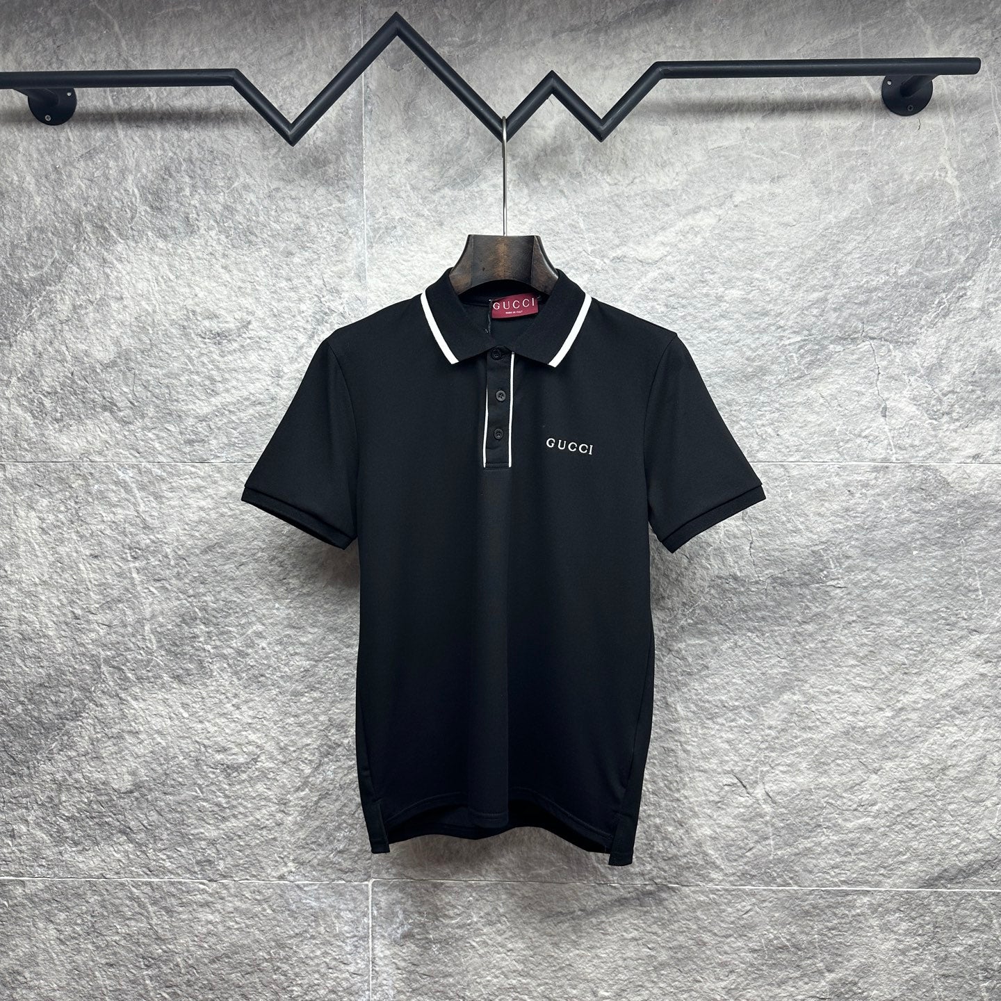 Black polo shirt with white collar trim, button placket, and Gucci logo