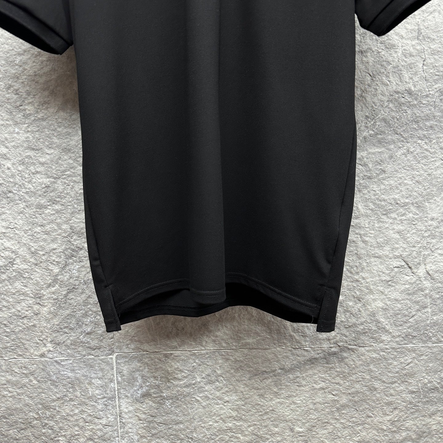 Black polo shirt hem with side slit detail