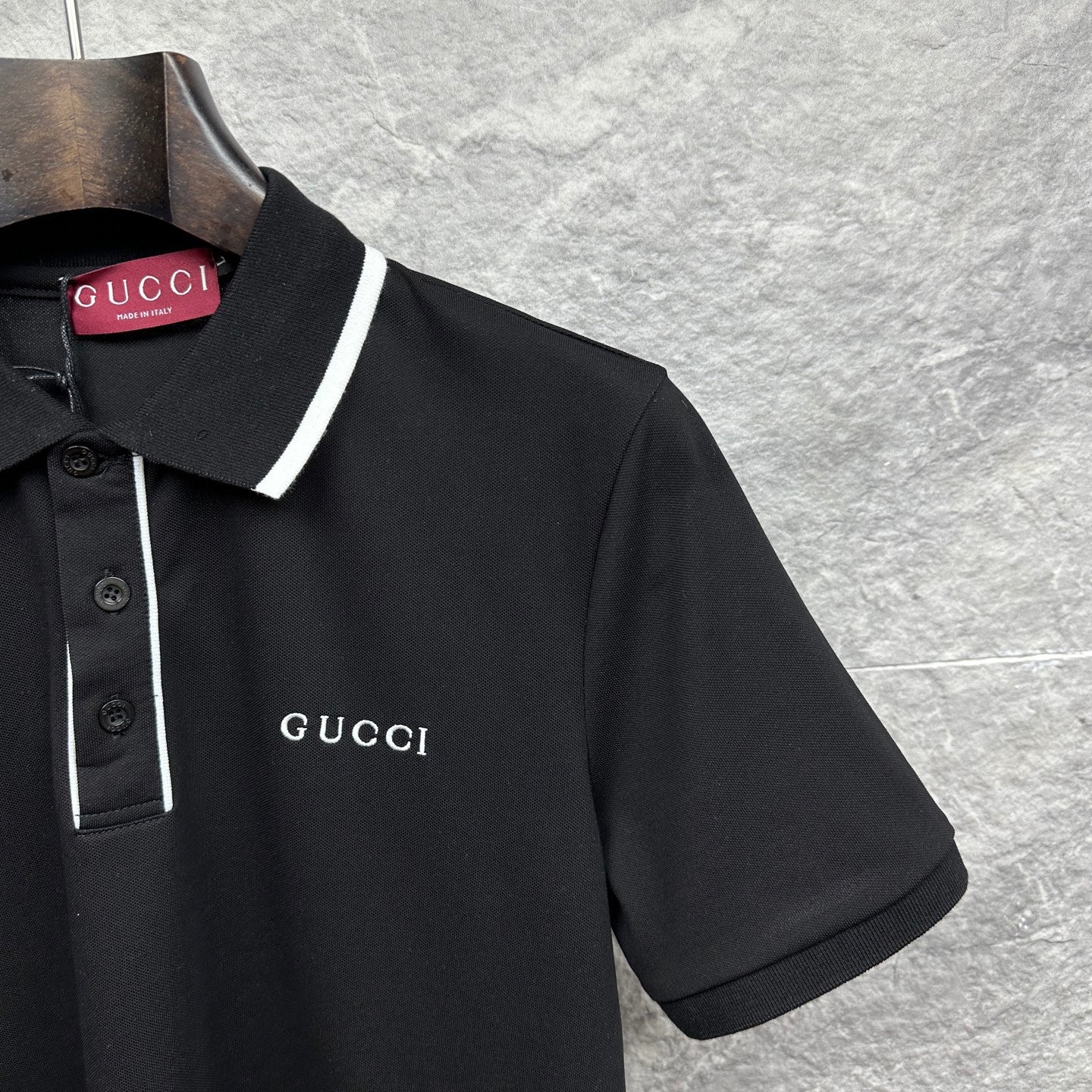 Black polo shirt chest with Gucci logo, white-trim collar, and short sleeves
