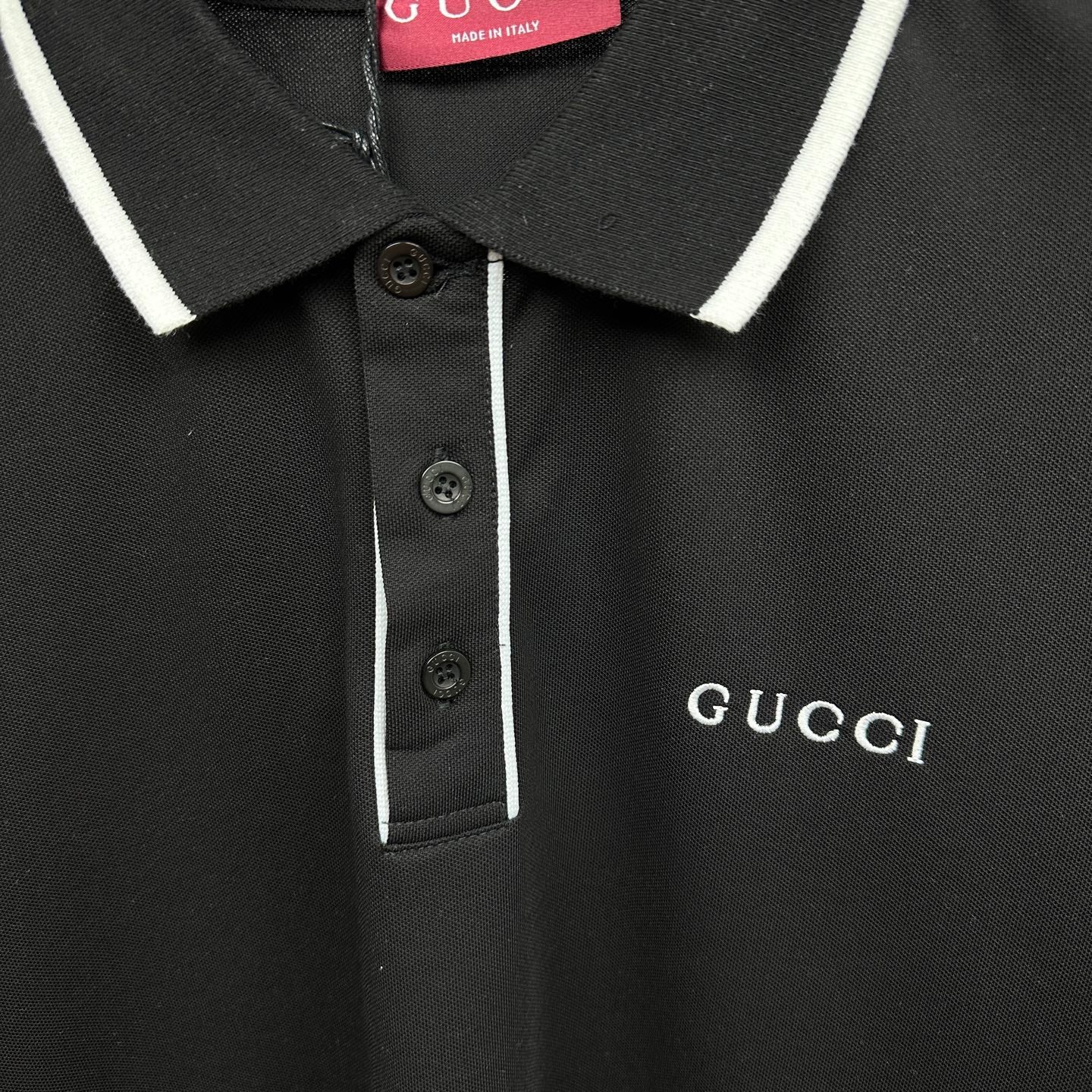 Black polo shirt button placket with white stripe and Gucci logo