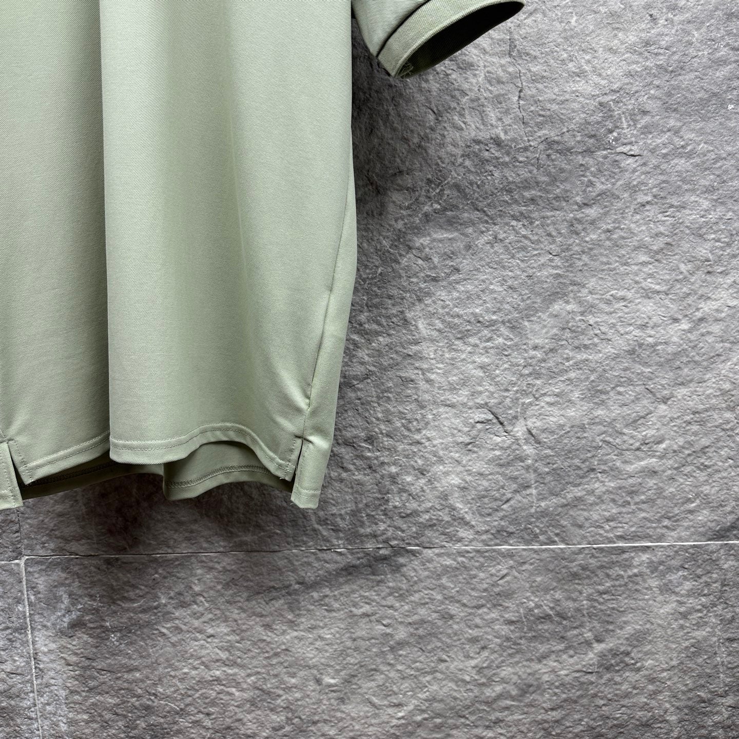 Mint green polo shirt partial view with curved hem and short sleeve
