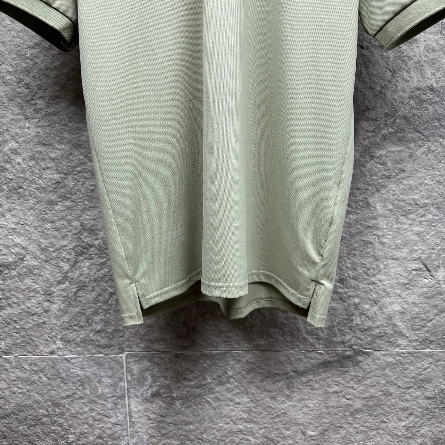 Mint green polo shirt hem with curved bottom and side seams