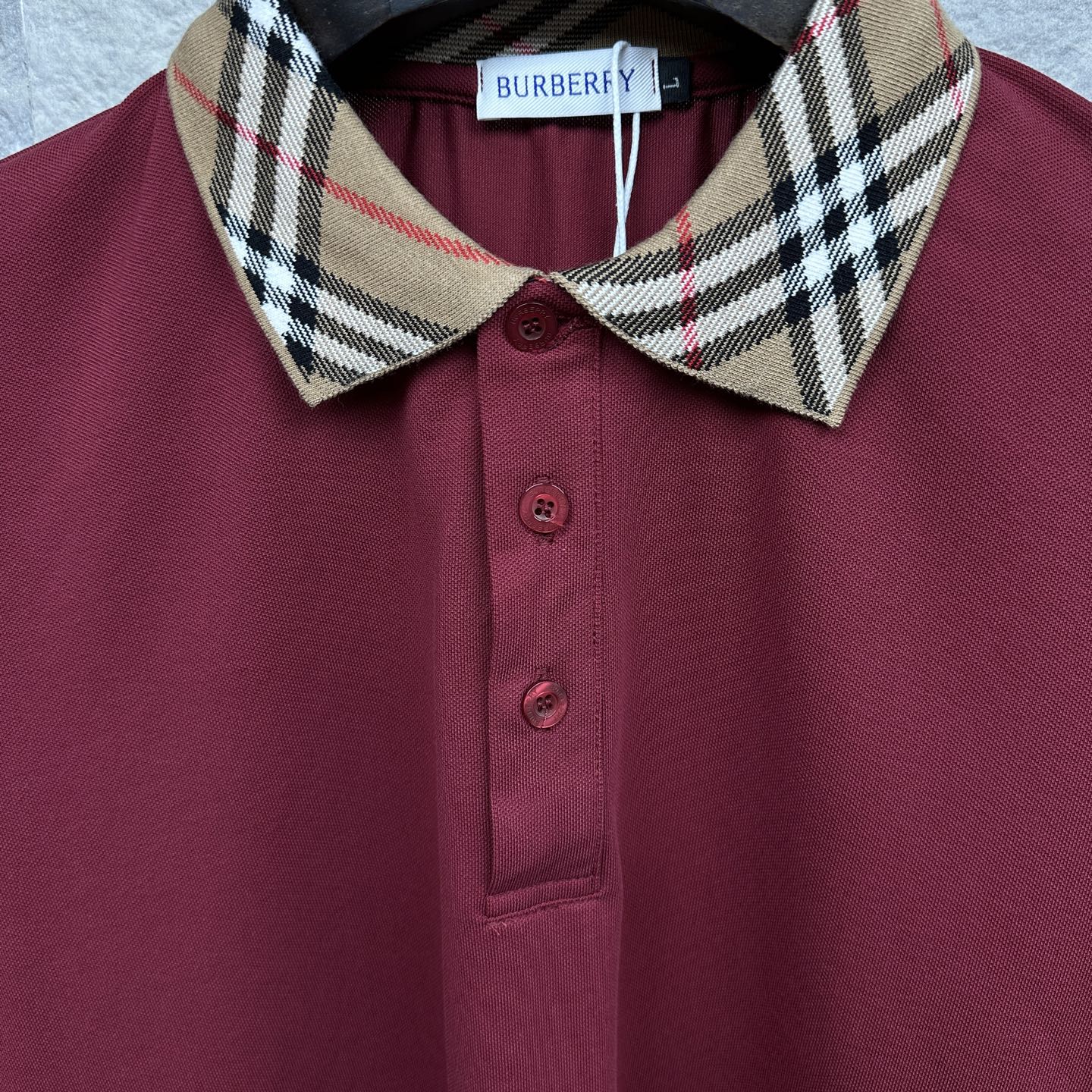 Maroon polo shirt close-up: check collar, Burberry label, and button placket.